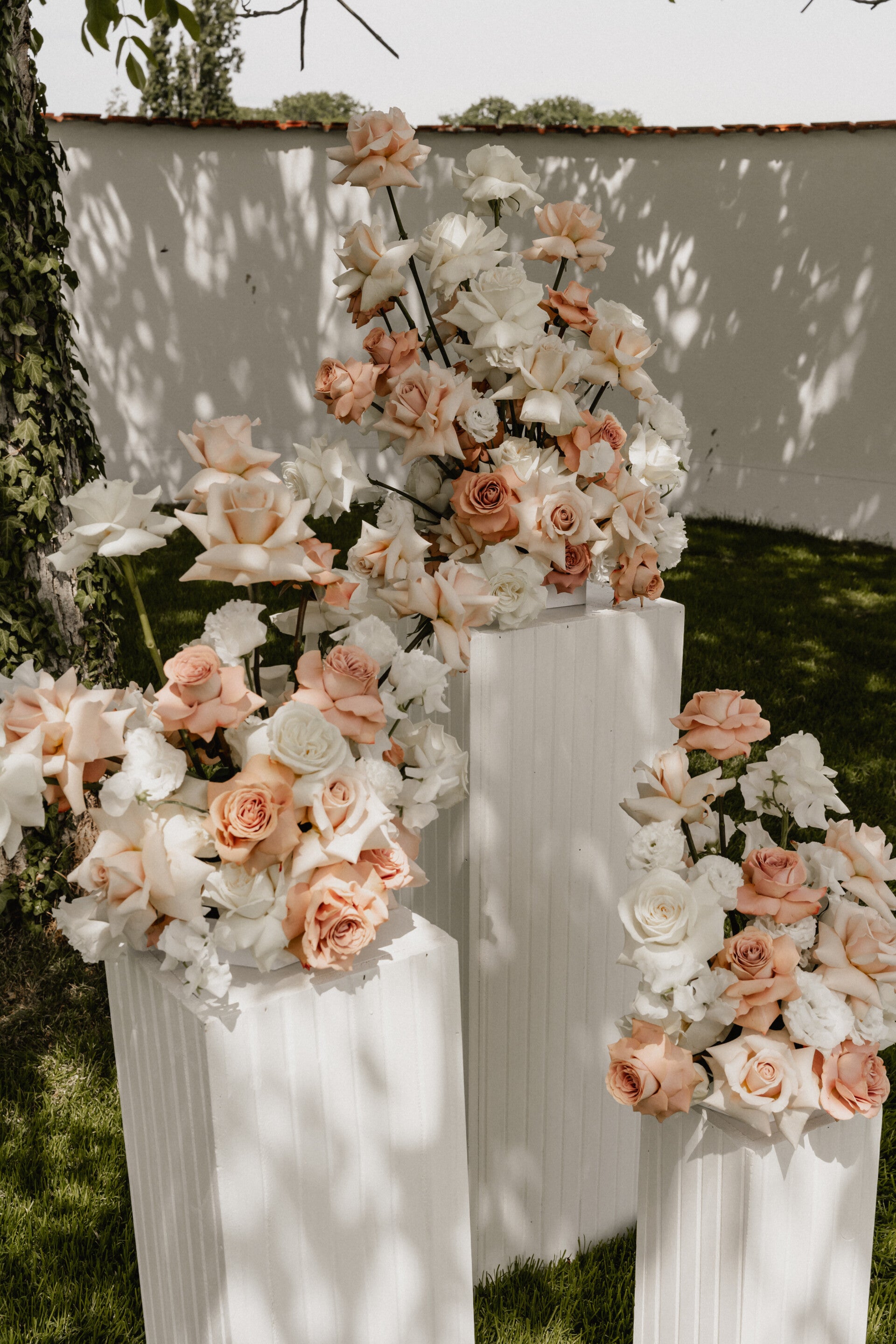 Rosa und weiße Rosen auf weißen Sockeln für eine Hochzeit