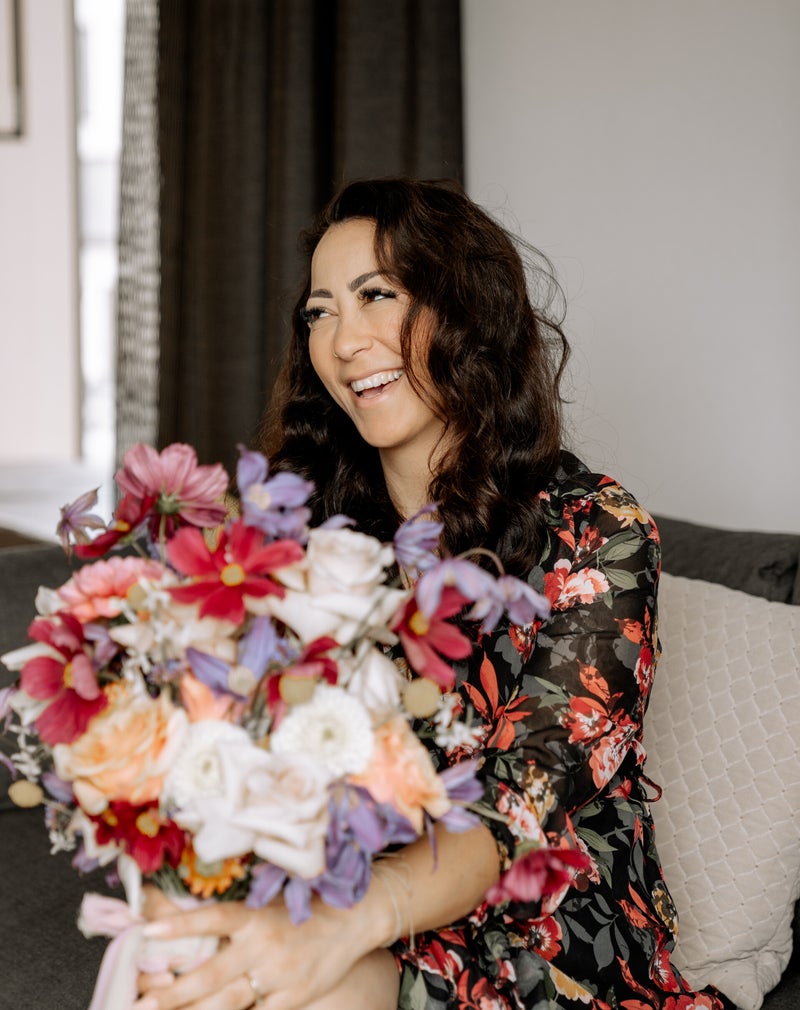 Halise Umur, Inhaberin von Blumen von Herzen, lächelnd mit einem bunten Blumenstrauß